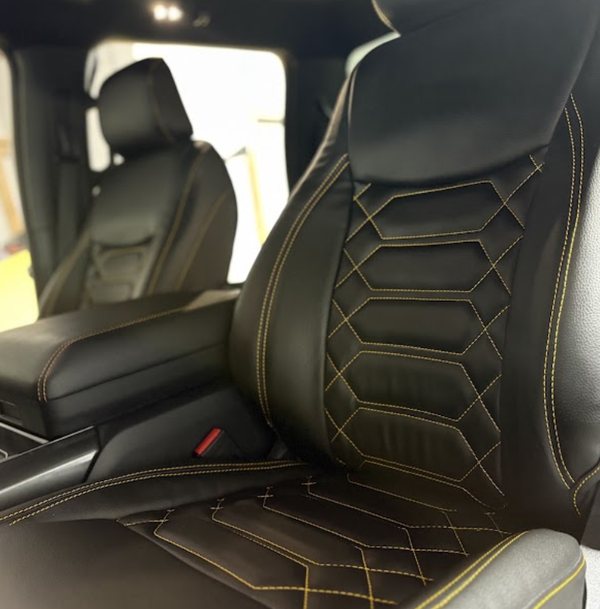 Black leather seat covers with gold hex stitching fitted in an SUV