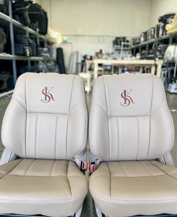 Cream leather seat covers with a custom embroidered monogram on the headrests